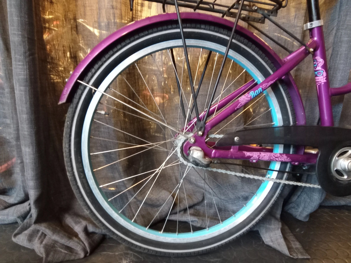 Lila cykel bakhjul med blå däckremsa och kedja