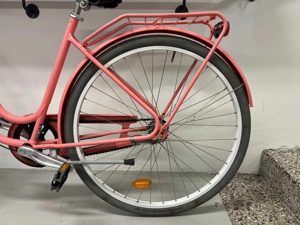 Rosa cykel med vitt däck, pakethållare och orange reflex på bakhjulet