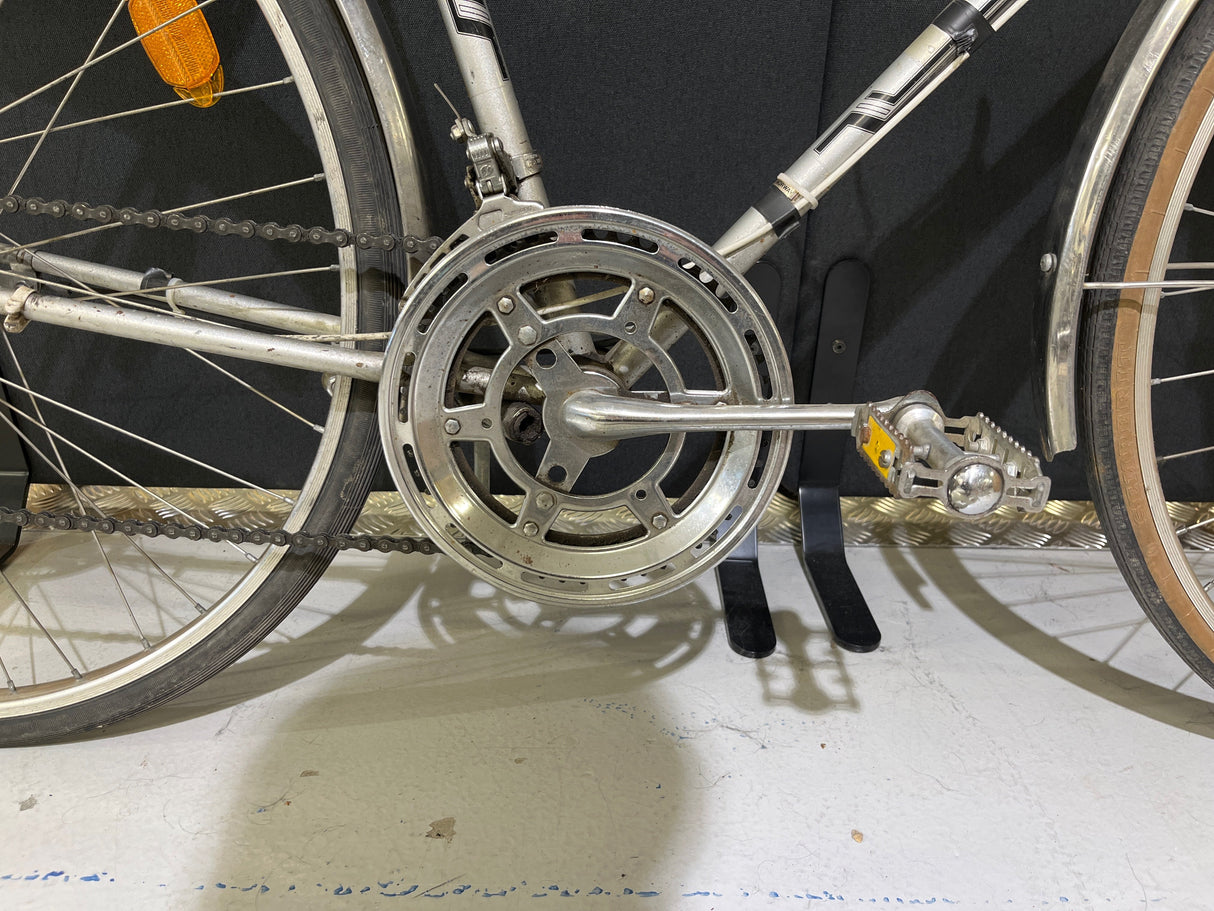 Närbild på cykelns kedja, vevparti och pedal med reflekterande orange och gul markering