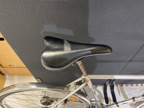 Svart cykelsadel på silverfärgad cykelram med skärmar och rostiga delar