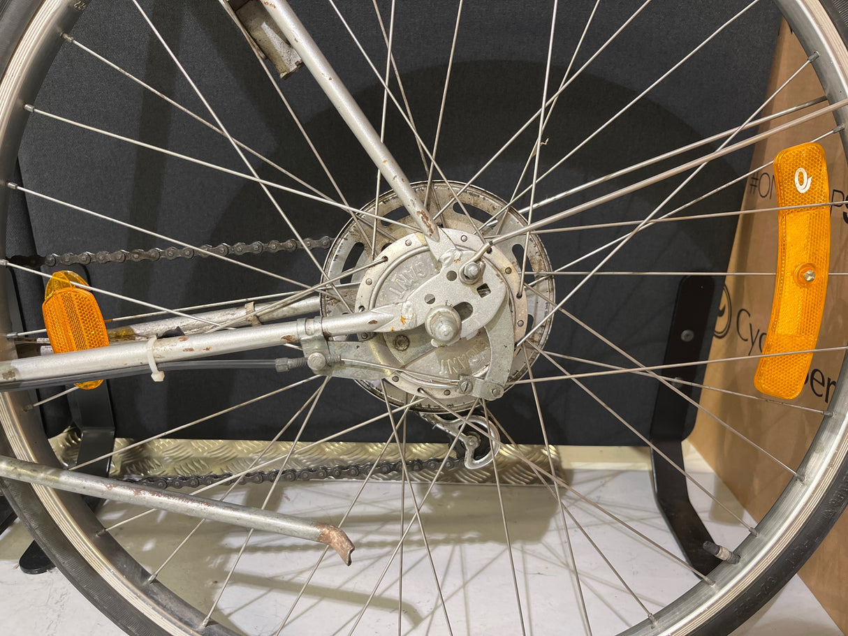 Närbild på cykelhjul med kedja, ekrar, broms och orange reflexer på cykelram