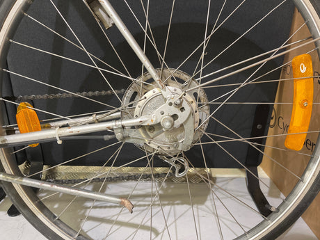 Närbild på cykelhjul med kedja, ekrar, broms och orange reflexer på cykelram