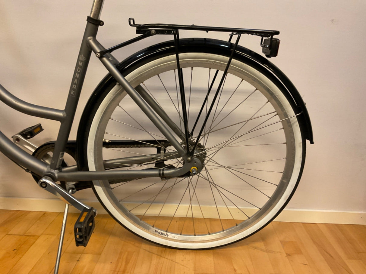Grå Monark cykel bakhjul med svart pakethållare, vit kant på däcket och pedal