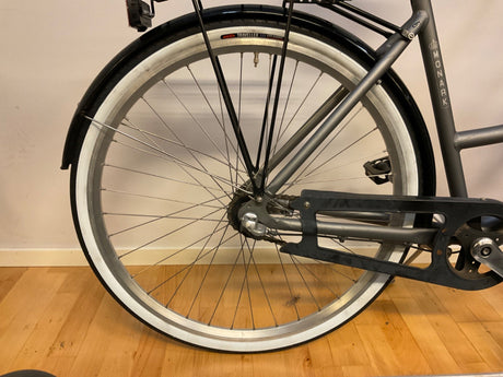 Bakhjul på Monark cykel med svart skärmskydd och kedja, vitt däck och svart kedjeskydd