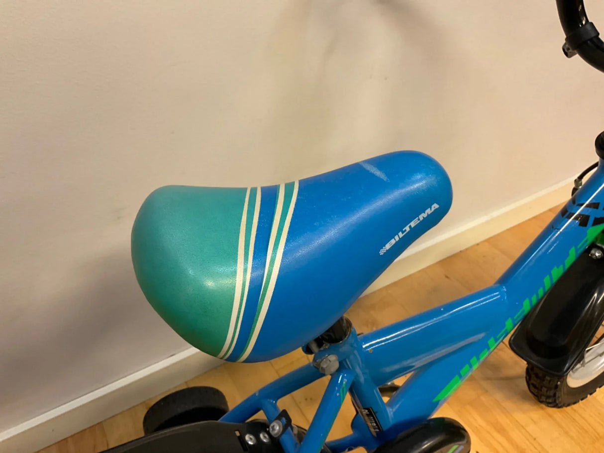 Blå och grön cykelsadel med vita ränder och texten Biltema på blå barncykel