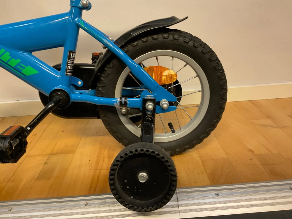 Bakdel av blå barncykel med stabila stödhjul och reflex på bakhjulet
