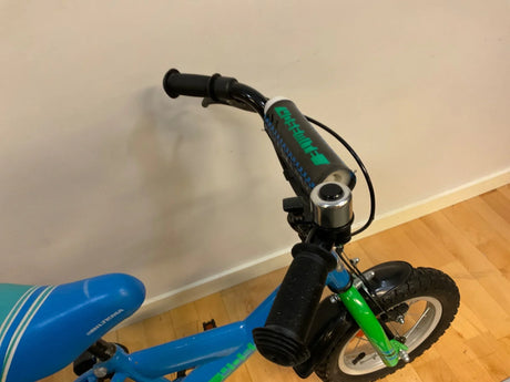 Barncykel med blå och grön ram, svart styre med skydd och blå sadel