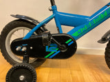 Blå barncykel med stödhjul, svart kedjeskydd med blå och gröna detaljer och nummer 12